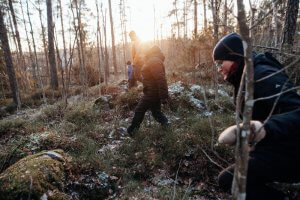 Henkilöitä kävelee metsässä harjoittelemassa etsintää.